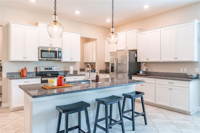 kitchen featuring white cabinetry, stainless steel appliances, and an island with sink