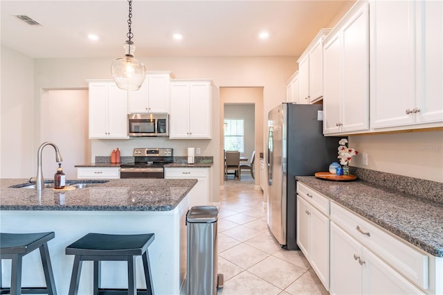 kitchen featuring sink, light tile patterned floors, appliances with stainless steel finishes, white cabinets, and dark stone counters