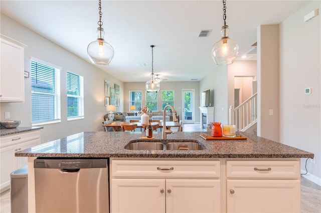 kitchen with white cabinetry, sink, hanging light fixtures, a kitchen island with sink, and stainless steel dishwasher