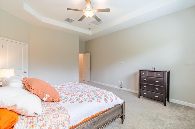 carpeted bedroom featuring ceiling fan and a tray ceiling