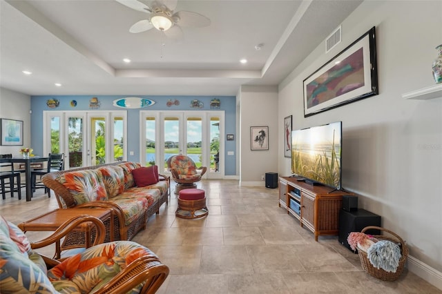 living room featuring ceiling fan, a raised ceiling, plenty of natural light, and french doors