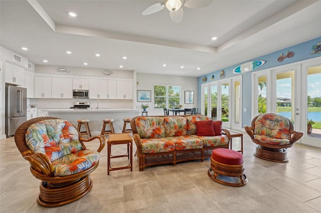 tiled living room with a tray ceiling and ceiling fan