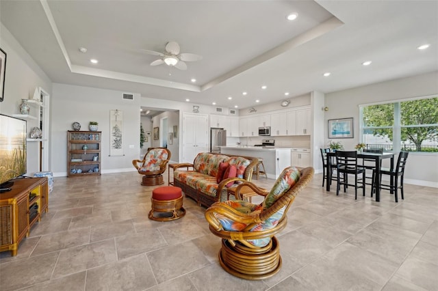 living room featuring a tray ceiling and ceiling fan