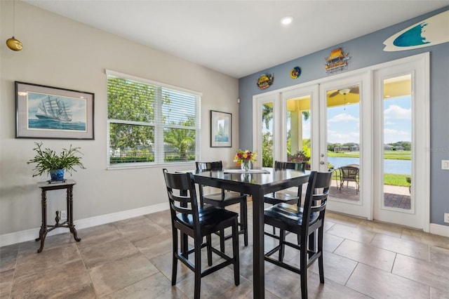 dining area with a wealth of natural light, a water view, and french doors