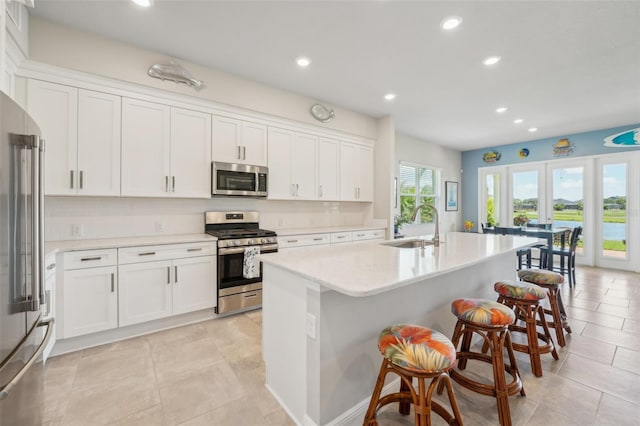 kitchen featuring a center island with sink, stainless steel appliances, and white cabinets