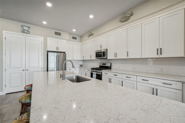 kitchen featuring light stone countertops, white cabinetry, appliances with stainless steel finishes, and sink