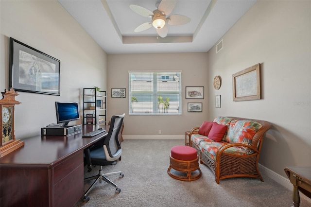 office area with light carpet, ceiling fan, and a raised ceiling