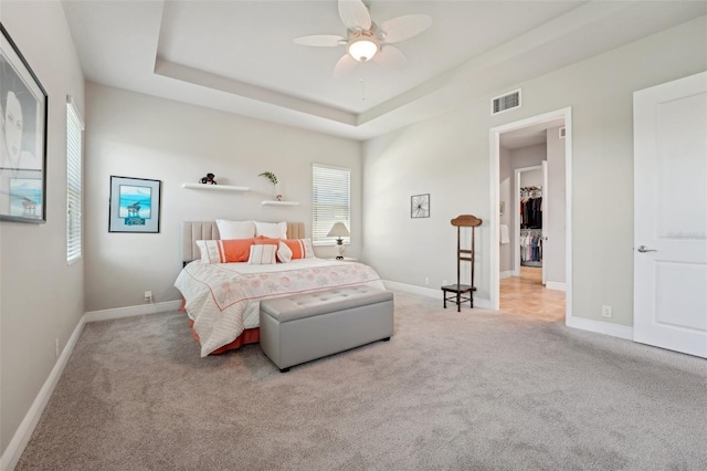 carpeted bedroom with ceiling fan and a tray ceiling