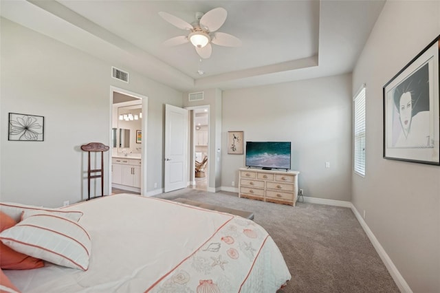 carpeted bedroom with connected bathroom, a tray ceiling, and ceiling fan