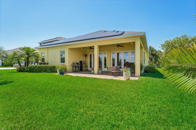 back of property featuring ceiling fan, solar panels, a yard, and a patio area