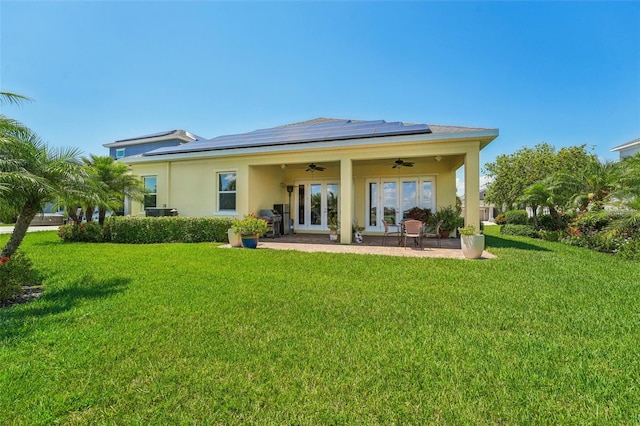 rear view of property featuring a patio, ceiling fan, solar panels, and a yard