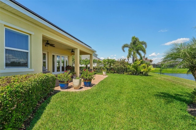 view of yard with a water view and ceiling fan