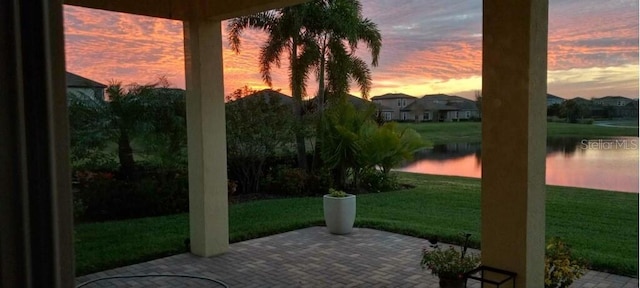 patio terrace at dusk with a lawn and a water view