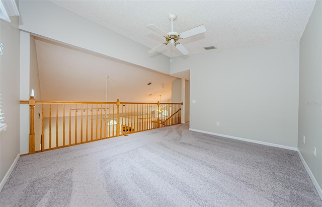 carpeted empty room with vaulted ceiling, a textured ceiling, and ceiling fan