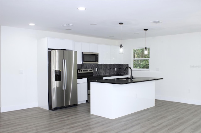 9085 Dorsey St, Spring Hill, FL 34608 - kitchen featuring appliances with stainless steel finishes, dark countertops, white cabinets, a center island with sink, and recessed lighting