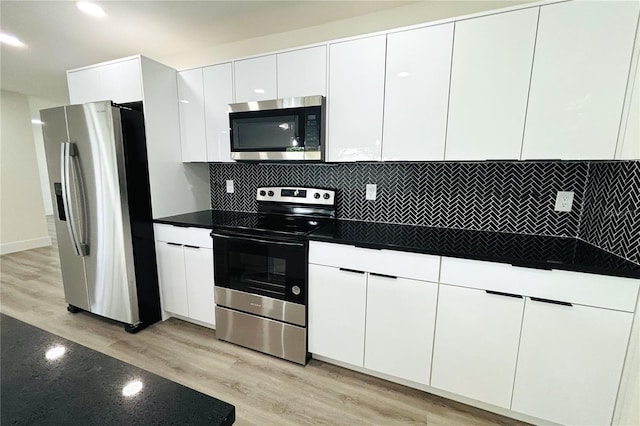 kitchen with light wood-type flooring, white cabinets, appliances with stainless steel finishes, and backsplash