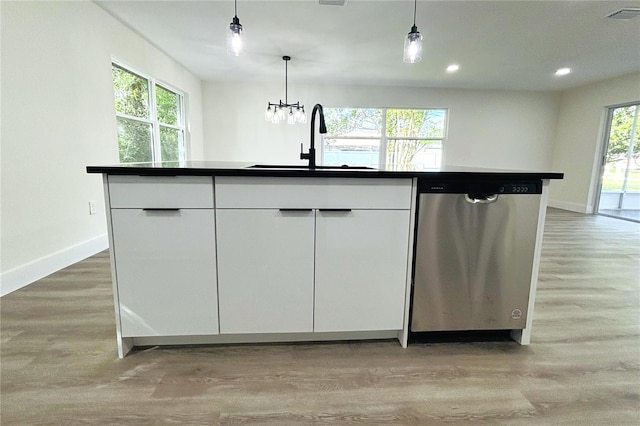 kitchen with dishwasher, a kitchen island with sink, a healthy amount of sunlight, and white cabinetry