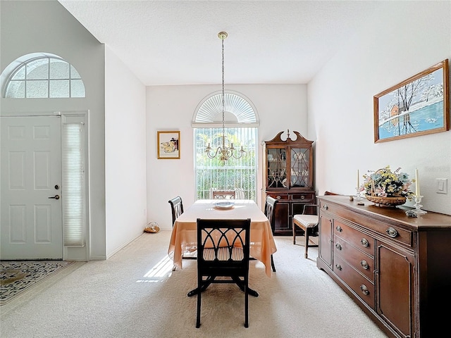 carpeted dining room with an inviting chandelier and a textured ceiling