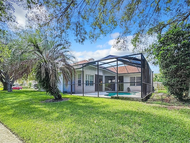 back of house with a patio, a lawn, and a lanai