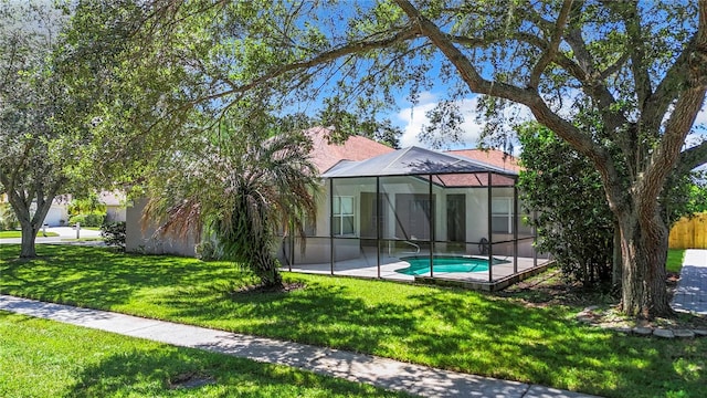 back of property featuring glass enclosure, a patio area, and a lawn