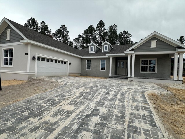 view of front of house featuring decorative driveway, an attached garage, and stucco siding