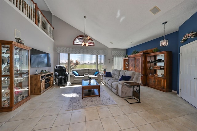 tiled living room with ceiling fan with notable chandelier and high vaulted ceiling