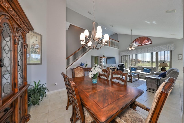 dining space with ceiling fan with notable chandelier, high vaulted ceiling, and light tile patterned floors