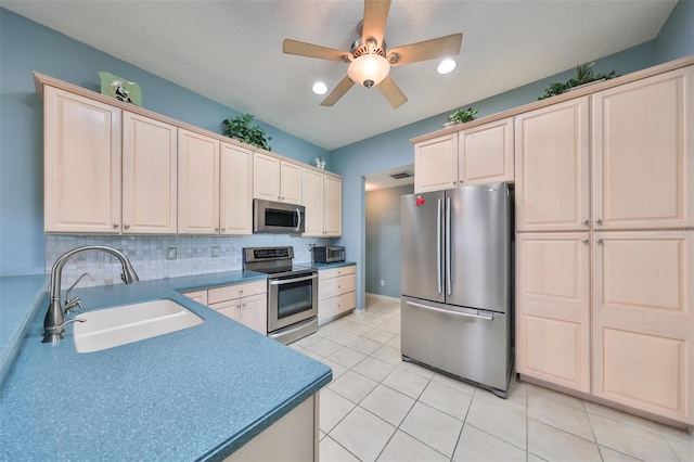 kitchen featuring ceiling fan, light tile patterned flooring, sink, appliances with stainless steel finishes, and decorative backsplash