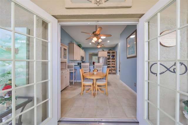 tiled dining room featuring ceiling fan and french doors