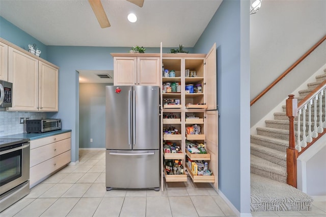 kitchen with decorative backsplash, light brown cabinetry, light tile patterned floors, and stainless steel appliances