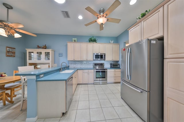 kitchen with light tile patterned floors, sink, backsplash, stainless steel appliances, and a kitchen bar