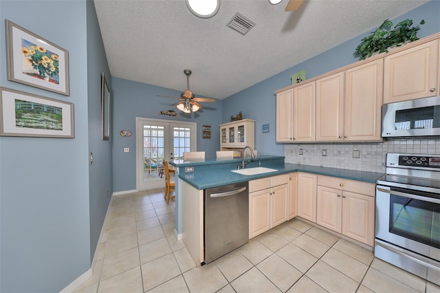 kitchen with a textured ceiling, light tile patterned flooring, kitchen peninsula, appliances with stainless steel finishes, and french doors