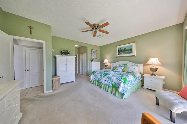 bedroom with ceiling fan, light colored carpet, and a textured ceiling