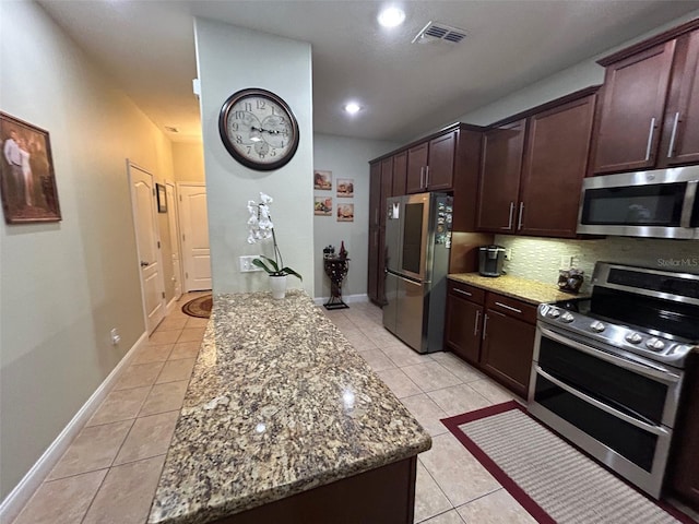 kitchen with decorative backsplash, stone countertops, light tile patterned floors, and stainless steel appliances