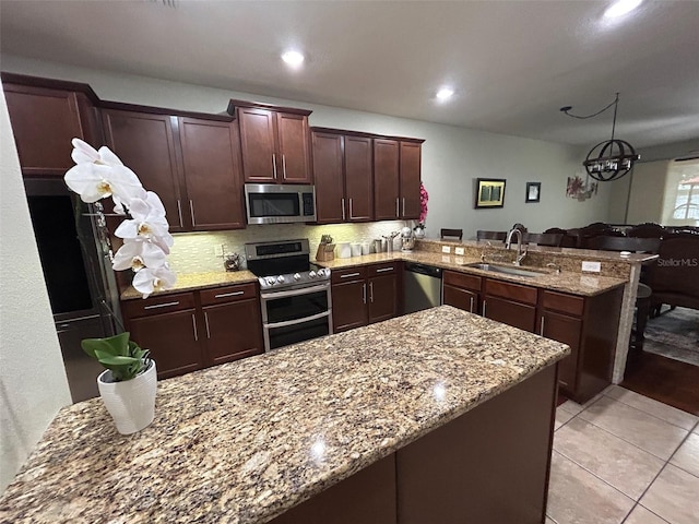 kitchen with dark brown cabinetry, sink, kitchen peninsula, stainless steel appliances, and light stone countertops