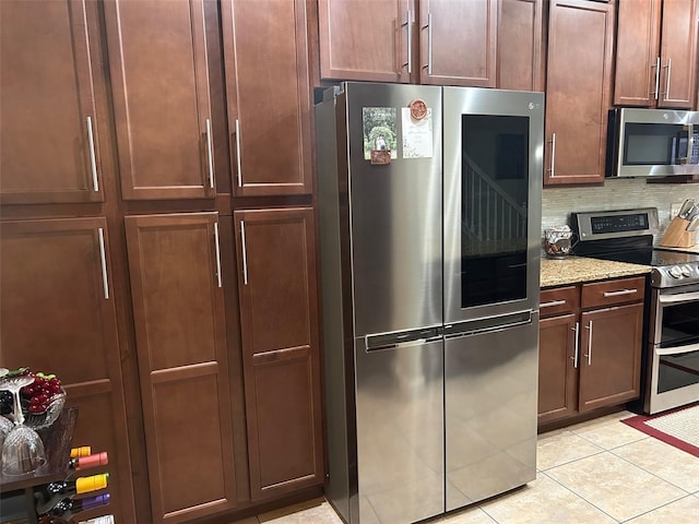 kitchen featuring light stone countertops, stainless steel appliances, light tile patterned floors, and decorative backsplash