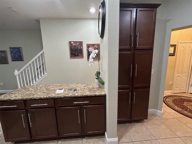 interior space with dark brown cabinetry, light tile patterned floors, and light stone counters