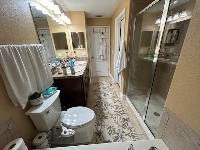 bathroom featuring tile patterned flooring, a shower with shower door, vanity, and toilet