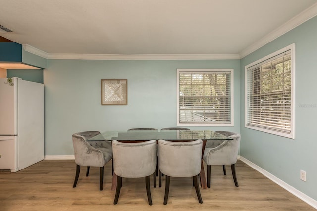 dining space with crown molding and light hardwood / wood-style floors