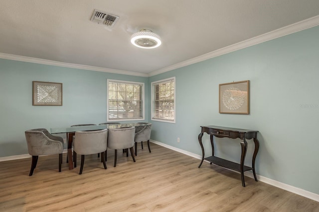 dining room with crown molding and light hardwood / wood-style flooring