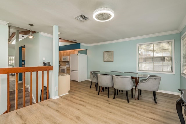 dining area featuring crown molding, light hardwood / wood-style flooring, and vaulted ceiling