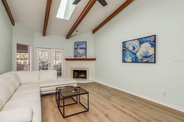 living room featuring french doors, a skylight, high vaulted ceiling, beam ceiling, and light hardwood / wood-style floors