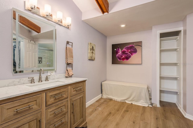 bathroom featuring vanity, wood-type flooring, and beamed ceiling