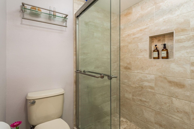 bathroom featuring toilet and an enclosed shower