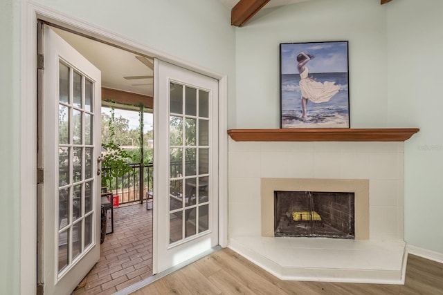 doorway to outside featuring hardwood / wood-style flooring, a tile fireplace, and beamed ceiling