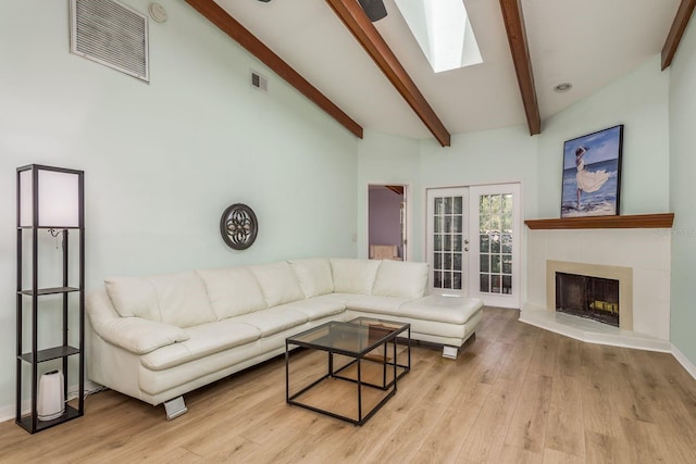 living room featuring beam ceiling, a skylight, high vaulted ceiling, french doors, and light wood-type flooring