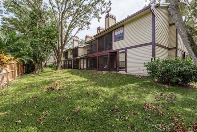 rear view of house with a sunroom and a lawn