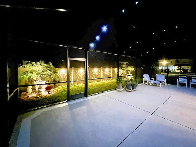 patio at night with a lanai and fence