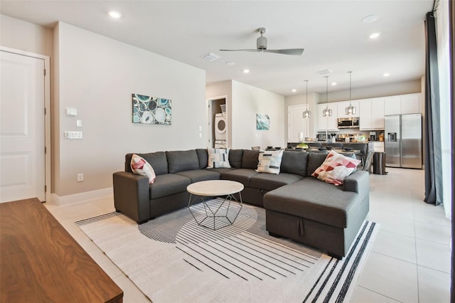 tiled living room featuring ceiling fan and stacked washer / drying machine