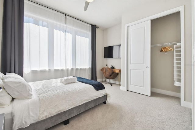 bedroom with ceiling fan, light colored carpet, and a closet